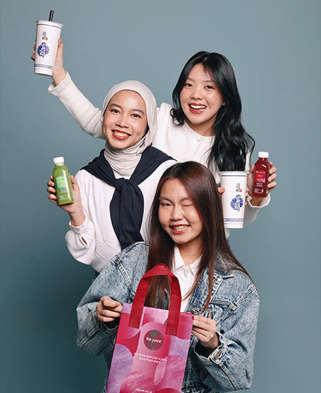 three girls smiling and holding rejuve juices and teazzi milk tea.